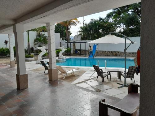 - une piscine avec des chaises et une table à côté d'une terrasse dans l'établissement Quinta Maria, à Fusagasuga