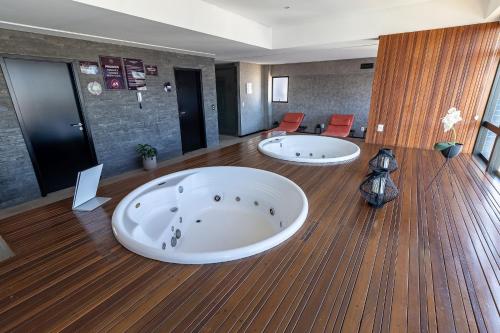 un ampio bagno con due grandi vasche su un pavimento in legno di Edificio Time maior area de lazer de Maceio a Maceió
