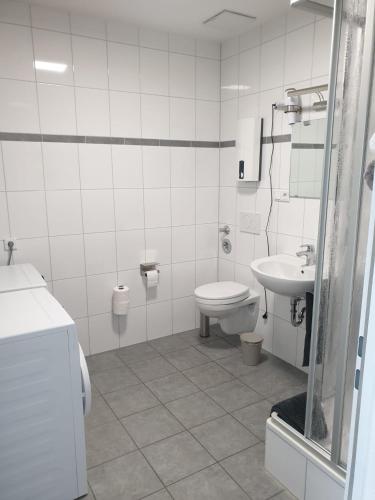 Un baño blanco con inodoro y lavabo. en Bataver, en Neuss