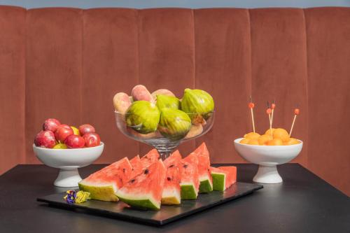 a table with bowls of fruit and a plate of watermelon at VIS Urban Suites&Spa in Bari
