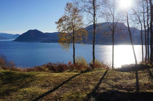 Blick auf einen See mit Bäumen und die Sonne in der Unterkunft Bregnehytte in Leikanger