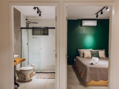 ブエノ・ブランダンにあるCasa Container com SPA e linda vista para a Serra da Mantiqueiraの緑の壁のベッドルーム1室、ベッド1台、シャワーが備わります。