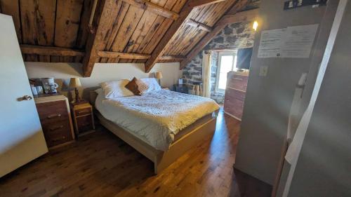a bedroom with a bed in a room with wooden ceilings at La Maison Rousseau in Montmagny