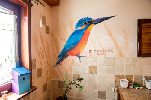 a painting of a colorful bird on the wall of a bathroom at Ptasi Dom — Saunowisko w Kępie in Świeszyno