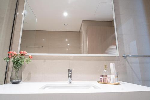 a bathroom sink with a mirror and a vase of flowers at FIRST CLASS 2BR with full BURJ KHALIFA view in Dubai