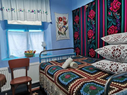 a blue bedroom with a bed and a chair at La Mădălina in Selemet