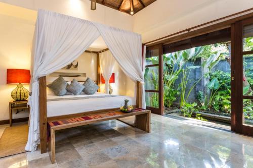 un dormitorio con una cama con dosel en Mango Tree Villas Jimbaran Bali, en Jimbaran