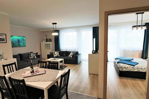 コウォブジェクにあるBliżej Morza Deluxe Apartmentyのリビングルーム(ダイニングテーブル付)、リビングルーム(ベッド1台付)
