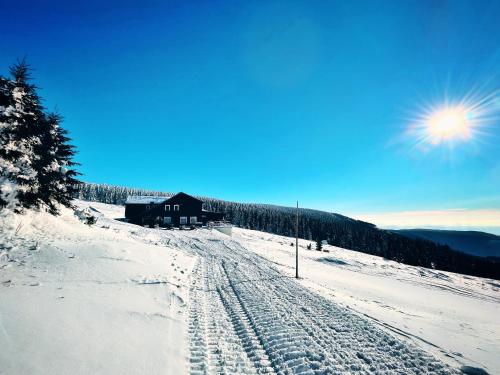 a snow covered slope with a building in the background at Horská bouda KUPROVKA in Strážné