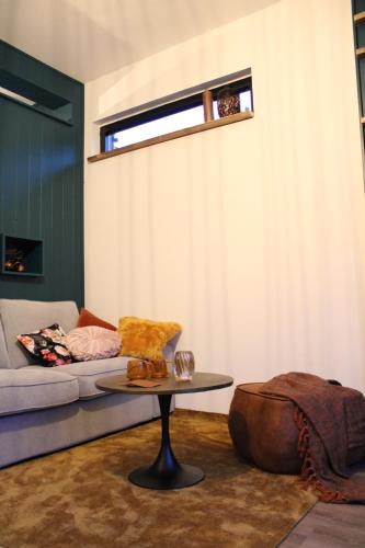 een woonkamer met een bank en een tafel bij Tiny House in de Boomgaard in Stad aan ʼt Haringvliet