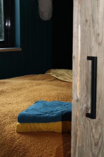 a bed with a blue towel sitting on it at Tiny House in de Boomgaard in Stad aan ʼt Haringvliet