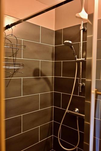 La salle de bains est pourvue d'une douche et d'un mur carrelé noir. dans l'établissement Gîte de charme 