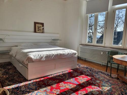 a bedroom with a bed and a table and windows at Le Chateau Blanc in Verviers