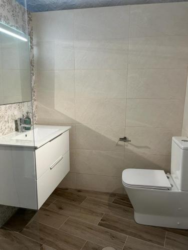 a bathroom with a white toilet and a sink at Cueva Lala in Granadilla de Abona