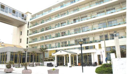 アギア・トリアダにあるサンタ ビーチ ホテルの白い大きな建物で、正面に中庭があります。