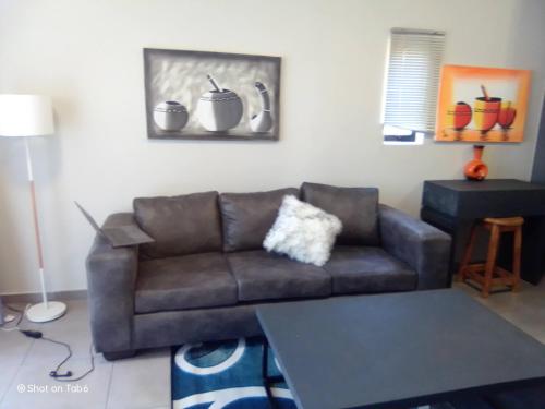 a living room with a brown couch and a table at Waterfall Ridge Apartments - Kick back and Relax in Midrand