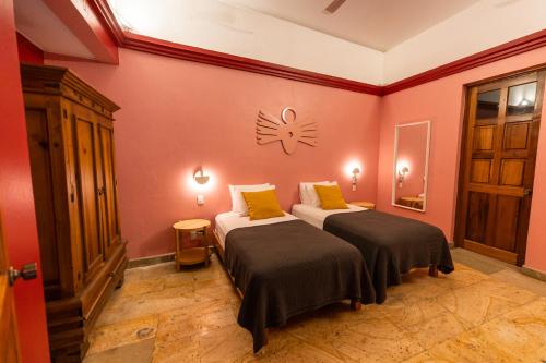 a room with two beds and a clock on the wall at Viajero Oaxaca Hostel in Oaxaca City