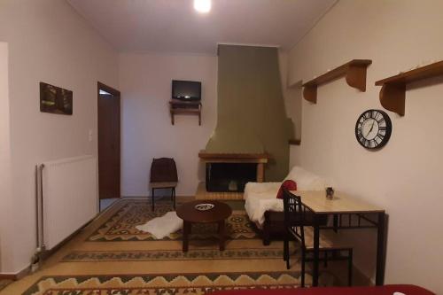 uma sala de estar com lareira e um relógio na parede em Ορεινό καταφύγιο Παρνασσού em Amfikleia