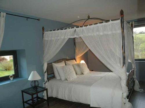a bedroom with a white bed with a canopy at Domaine de Godchure - Gîte & Spa 