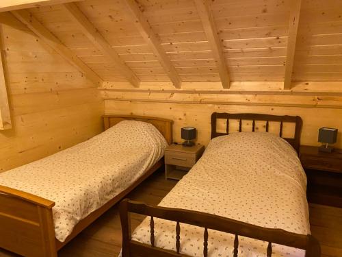 2 camas en una habitación con paredes de madera en Gîte Sous-Poupet, 