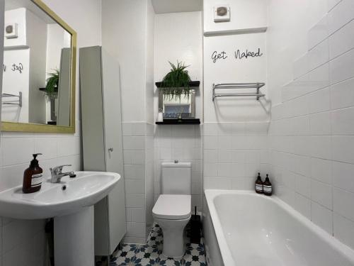 uma casa de banho com um lavatório, uma banheira e um WC. em Central Welling Flat em Welling