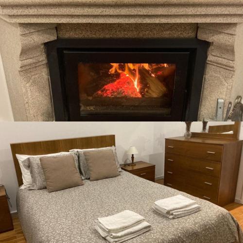 a bedroom with a fireplace and a bed with towels on it at Casa de Casarelhos - Andar da Moradia com terraço - Vistas rio - "Gerês" in Geres