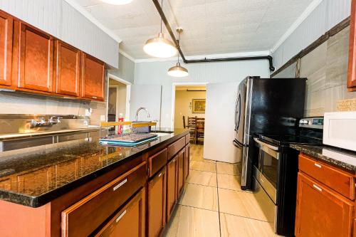 a large kitchen with wooden cabinets and a black refrigerator at Unique Large 9BR House with 3 Bath Close to the falls in Niagara Falls
