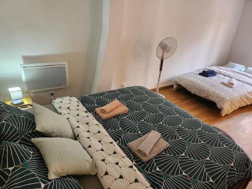 a bedroom with a bed with pillows and a fan at Duplex confortable proche Paris in La Courneuve