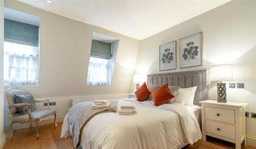 a bedroom with a bed and a chair and two windows at Shepherd Street, Mayfair in London