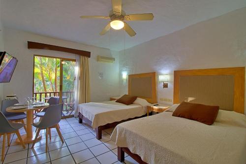 a hotel room with two beds and a table at Hermoso alojamiento en los Tules, frente al mar en medio de hermosos jardines, es Unico!!! in Puerto Vallarta