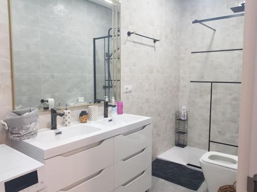 a white bathroom with a sink and a toilet at Mar y Sol Suites in Grao de Castellón