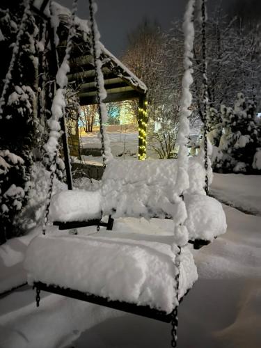 a swing covered in snow in front of a gazebo at Rodinné apartmány Rafael Bedřichov in Bedřichov