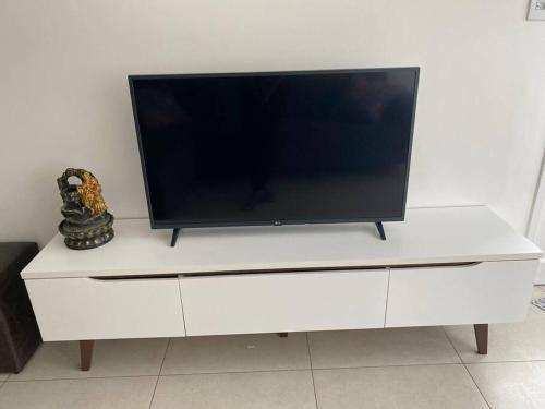 a flat screen tv sitting on top of a white dresser at Apto frente Praia Itararé in São Vicente