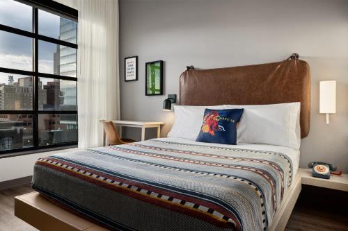 1 dormitorio con 1 cama grande y ventana grande en Moxy Omaha Downtown en Omaha