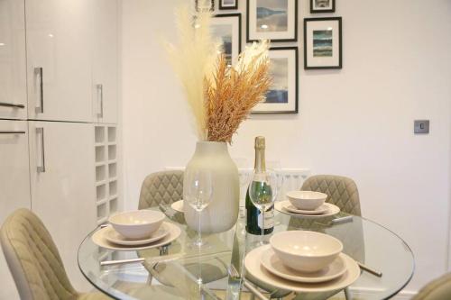 a glass table with a vase and bowls and a bottle of wine at Luxurious Townhouse In Central Manchester in Manchester