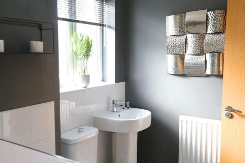 a bathroom with a sink and a toilet and a window at Luxurious Townhouse In Central Manchester in Manchester