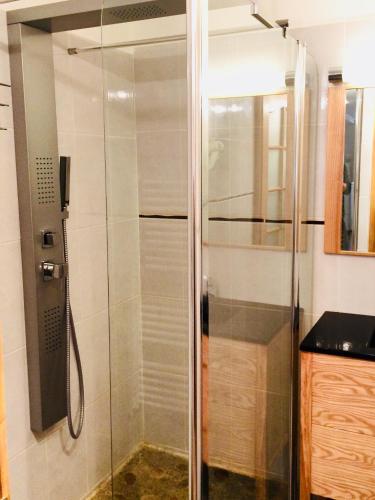 une douche avec une porte vitrée dans une salle de bain dans l'établissement Les Gîtes du Moulin d Olt, à La Canourgue