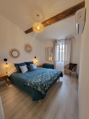 een slaapkamer met een bed met een blauw dekbed bij Maison de ville standing proche mer in Florensac