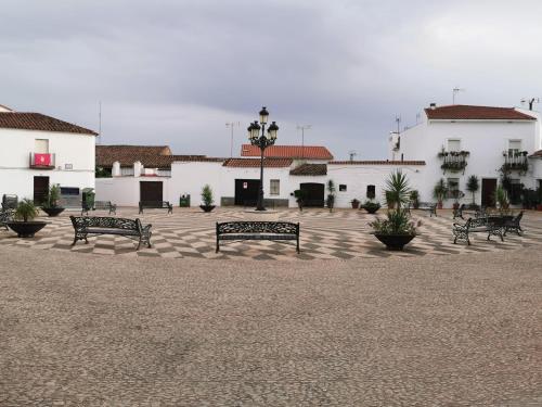 un grupo de bancos en un patio con edificios en Casa rural Cañaveral de León, en Cañaveral de León