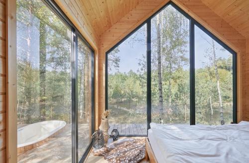 a glass house with a tub and a bedroom at Forestic Lietuva in Vilionys
