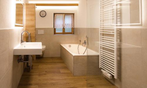 ein Badezimmer mit einem Waschbecken, einer Badewanne und einem Spiegel in der Unterkunft Auf der Tannermühle in Bayrischzell