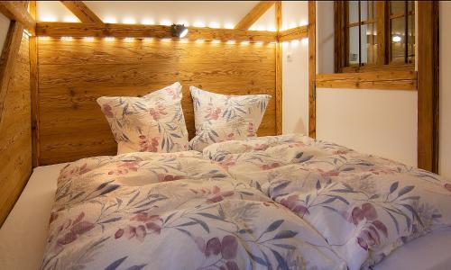 Schlafzimmer mit einem Bett mit einem Kopfteil aus Holz und Kissen in der Unterkunft Auf der Tannermühle in Bayrischzell