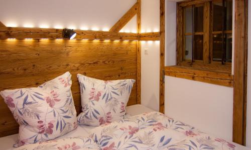 ein Schlafzimmer mit einem Bett mit zwei Kissen und einem Fenster in der Unterkunft Auf der Tannermühle in Bayrischzell