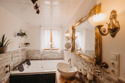 a bathroom with a tub and a sink and a mirror at Altes Häusle am Waschbach Ferienwohnungen in Edenkoben