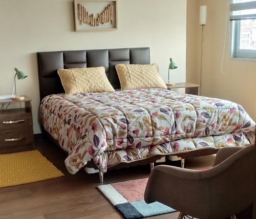 a bedroom with a bed with a comforter and a chair at Acogedoras vistas al illimani, cálido y accesible in La Paz