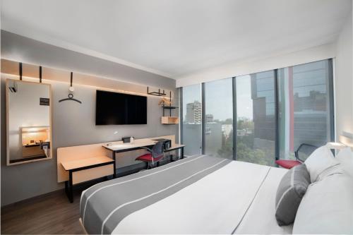 a hotel room with a bed and a desk with a computer at City Express Plus by Marriott Insurgentes Sur in Mexico City