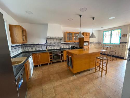 a large kitchen with wooden cabinets and a counter top at Bungalow familiar con piscina in San Juan de Alicante