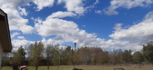 a blue sky with clouds and trees in a field at Cabaña Precordillera Cunco in Cunco