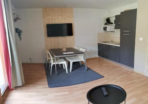 Il comprend un petit salon avec une table et une cuisine. dans l'établissement Superbe appartement en résidence avec piscine LES ORRES 1800, aux Orres