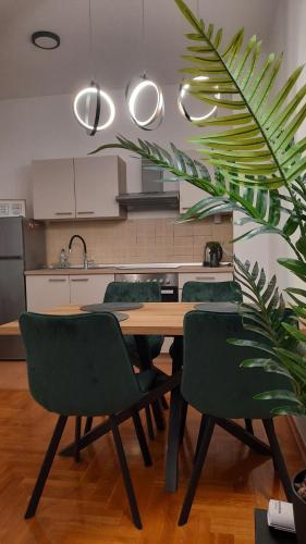 a kitchen with a wooden table and green chairs at Apartman Tena in Vukovar